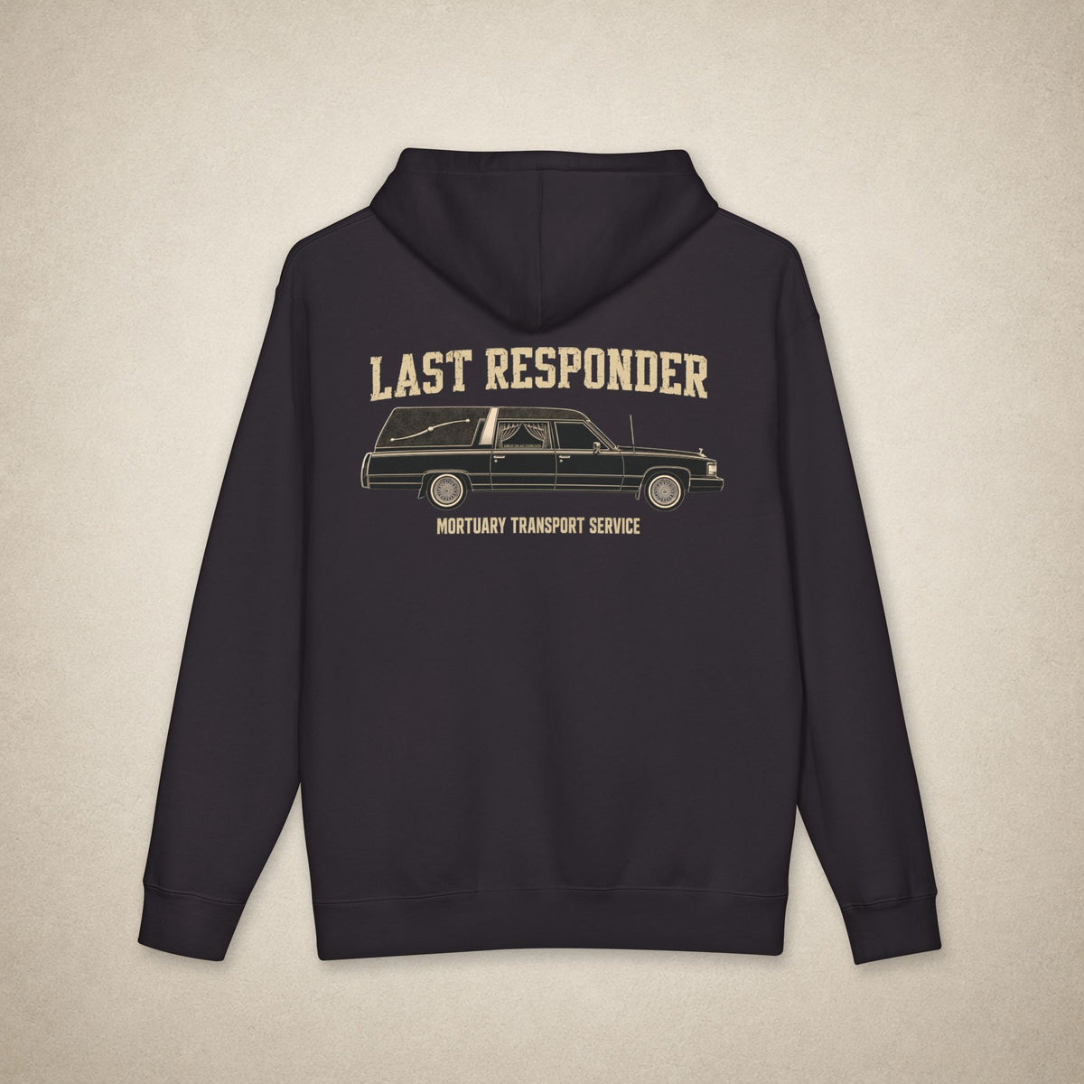 A dark navy blue hoodie shown from the back, featuring a vintage-style graphic of a hearse with the text 'LAST RESPONDER' and 'MORTUARY TRANSPORT SERVICE' in a beige color, set against a textured light beige background.