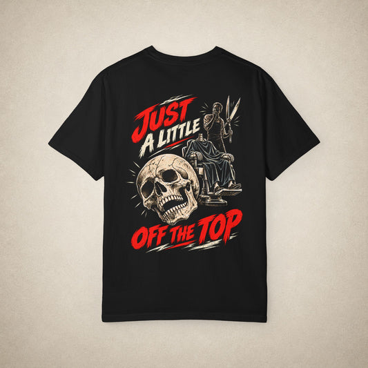 A black short-sleeve graphic t-shirt laid flat against a textured beige background. The front of the shirt features a large graphic print with a skull, a statue, and bold red and white text reading 'JUST A LITTLE OFF THE TOP'.