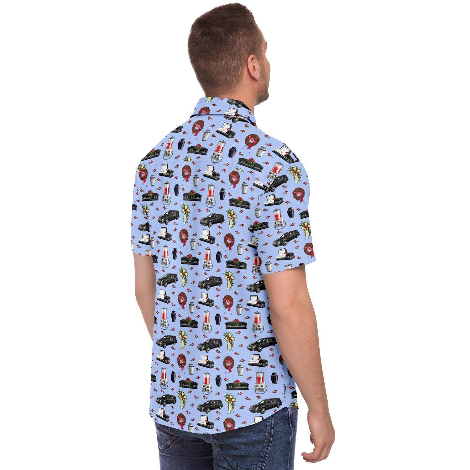 Back view. Model with light blue button up shirt with funeral pattern containing hearse, casket, coffin, flower cross easel, red rose wreath, embalming machine, cremation urn