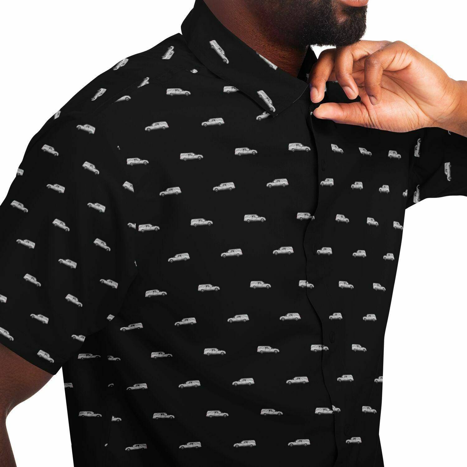 male model with a black short sleeve button up tee shirt with a silver grey funeral hearse pattern. Close up side angle view.